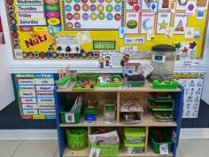 a classroom desk with lots of toys and books on it's shelves in front of a bulletin board