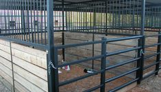 the inside of a metal fenced in area with wood planks and steel bars