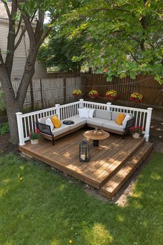 a wooden deck with two couches and a coffee table on it next to a tree