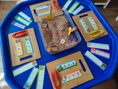 a blue tray topped with lots of different items on top of a wooden table next to scissors