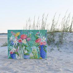 there is a painting on the sand with flowers in vases and blue pots next to it