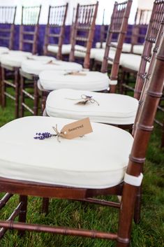 rows of wooden chairs with white covers and lavender flowers tied to them