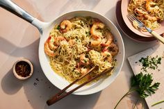 a bowl of shrimp and noodles with chopsticks next to it on a table