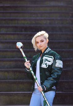 a woman with blonde hair holding two baseball bats and posing in front of some stairs