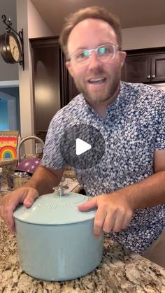 a man wearing glasses is making something in a blue casserole dish on the kitchen counter