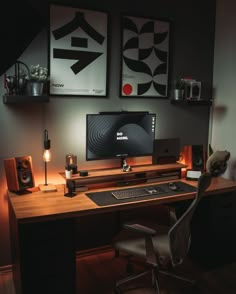 a desk with a computer and speakers on it in front of two framed art pieces