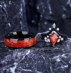 two rings sitting on top of a rock next to each other with red and black stones