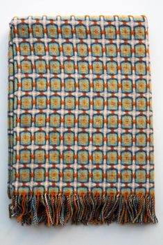 an orange, blue and white plaid blanket with fringes on the bottom is shown