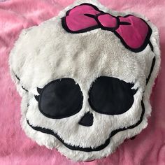 a white skull with a pink bow on it's head sitting on a pink blanket