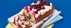 a piece of cake with white frosting and berries on top sits on a yellow napkin next to a knife