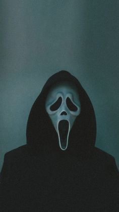 a person wearing a ghost mask with their mouth open in front of a dark background