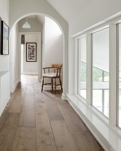 a chair sitting in the middle of a hallway between two walls with large windows on each side