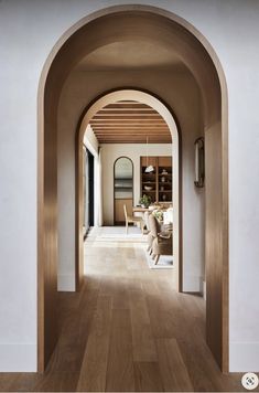 an archway leads to the dining room and living room in this modern house with wood flooring