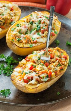 three stuffed squash halves on a plate with carrots in the background