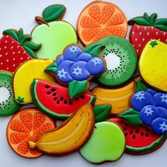 decorated cookies are arranged in the shape of fruit