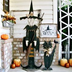 a porch decorated for halloween with pumpkins and witch statues on the front steps,