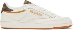 Low-top paneled grained leather sneakers in white and brown. · Perforated detailing at toe · Lace-up closure · Padded tongue and collar · Logo embossed at heel tab · Textile logo patch at outer side · Terry cloth lining · Treaded rubber sole Supplier color: Chalk/Reebok Gum/Retro gold Off White Reebok, Classic Low-top Sneakers With Logo Patch, Vintage Reebok Sweatshirt, Men’s Reebok Sneakers, Reebok Club C 85, Club C 85, Reebok Classic Leather, Reebok Classics, Reebok Club C