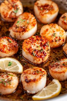 sea scallops are cooked in a pan with lemon wedges and parsley