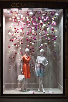 two mannequins in front of a display window with pink and white flowers