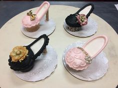 three cupcakes decorated with shoes and flowers on top of lace doily plates