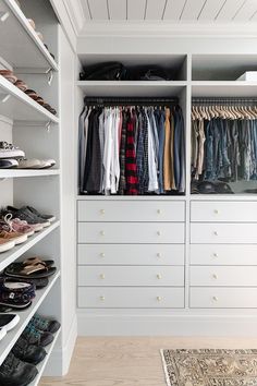 a walk in closet with lots of clothes and shoes on the shelves next to it