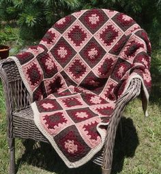 a crocheted blanket sitting on top of a wicker chair in the grass