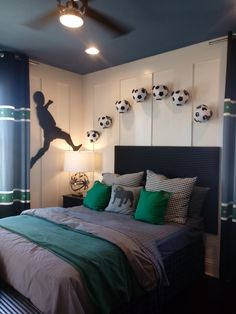 a bedroom with a soccer themed wall hanging above the headboard and ceiling fan, along with two lamps on either side of the bed