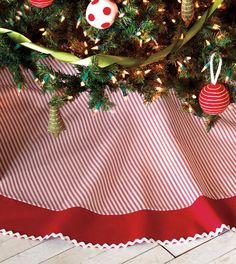 a christmas tree with ornaments hanging from it's branches on a red and white table cloth