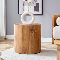 a wooden table with a vase on top of it in front of a painting and chair