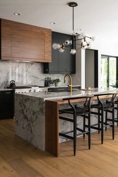 a kitchen with marble counter tops and black chairs