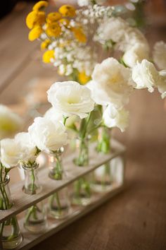 several vases filled with white and yellow flowers