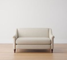 a white couch sitting on top of a hard wood floor next to a wall in an empty room