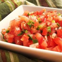 a white bowl filled with chopped tomatoes and green onions