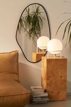 a table lamp sitting on top of a wooden block next to a mirror and couch