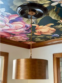 a lamp hanging from the ceiling in a room with flowers painted on the ceiling and walls