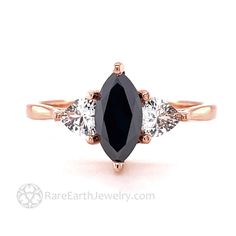 an oval black diamond ring with three pear shaped diamonds on the side and two round white diamonds