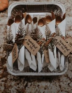 forks and spoons are wrapped in brown paper with pine cones on them, tied with twine