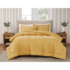 a bed with yellow comforters and pillows