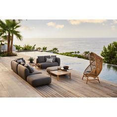 an outdoor living area with couches, tables and chairs on the deck overlooking the ocean