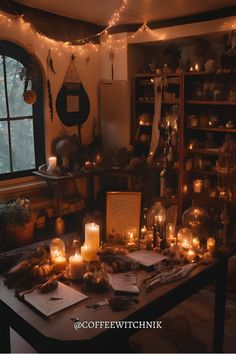 a table topped with lots of candles next to a window filled with books and pictures