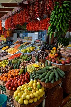 an outdoor market with many different types of fruits and vegetables in baskets on the tables