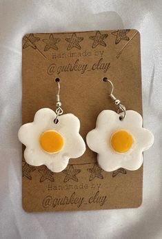 two fried eggs in the shape of flowers are hanging from earwires on a card