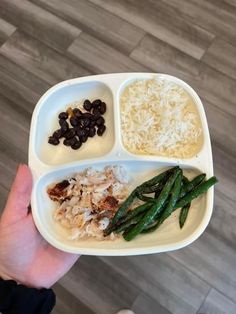 a person holding up a plate with rice, beans and other food items on it