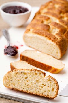 sliced loaf of bread sitting on top of a cutting board next to a bowl of jam