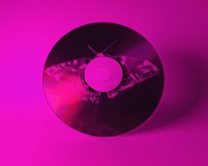 a purple disc with a small insect on it's side and a pink light in the background