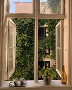 an open window with plants in it and a vase on the table next to it