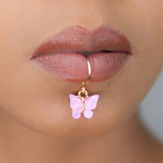 a woman's lip with a pink butterfly charm attached to it