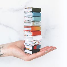 a person's hand holding a stack of books in front of a marble background