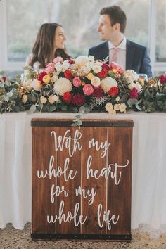 a man and woman sitting at a table with flowers in front of them that says, not all my whole heart for my whole life