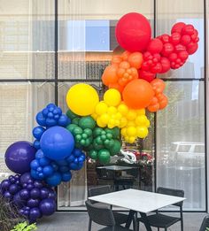 the balloons are all over the table and chairs in front of the glass wall that looks like it is floating